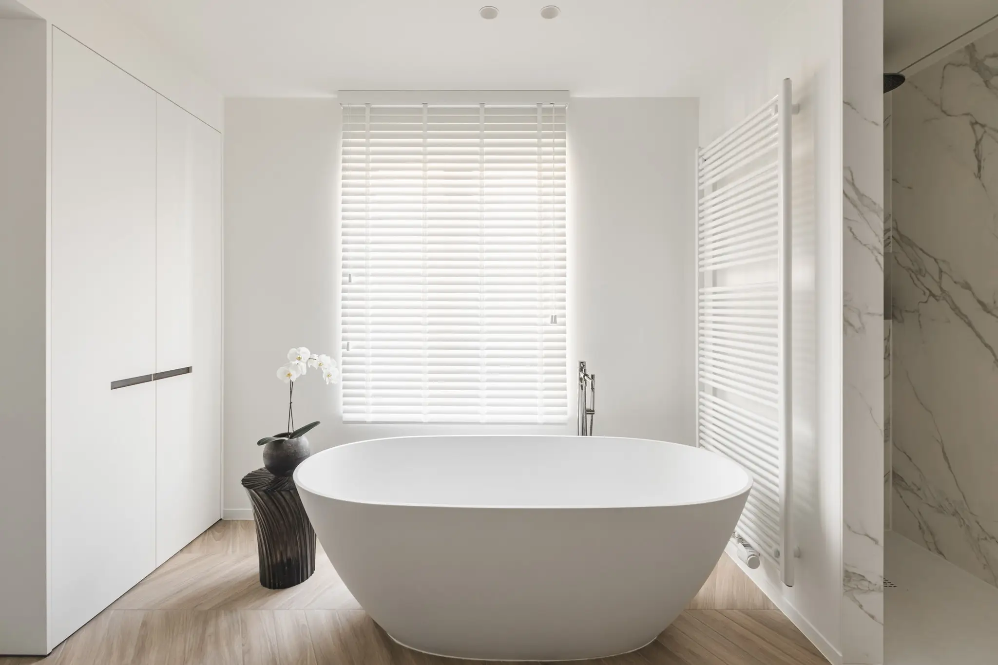 Badkamer met een vrijstaand bad en marmer aan de muur