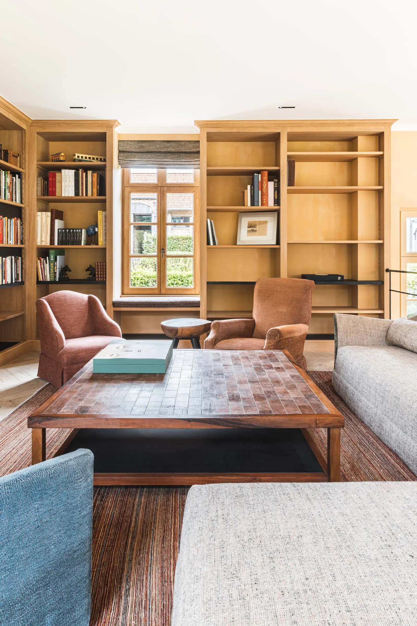 Bibliotheek met houten boekenkasten, roze fauteuils en een salontafel