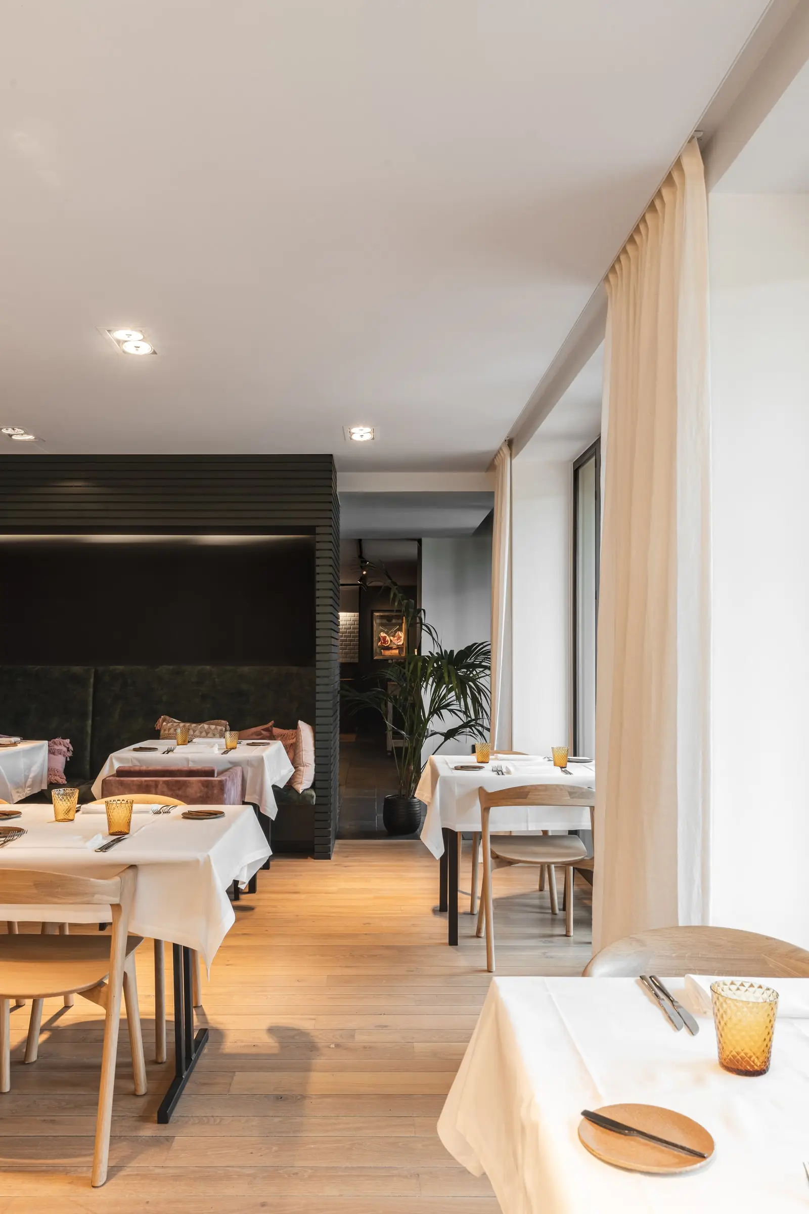 Witte gordijnen langs de ramen van de eetzaal, met gedekte tafels