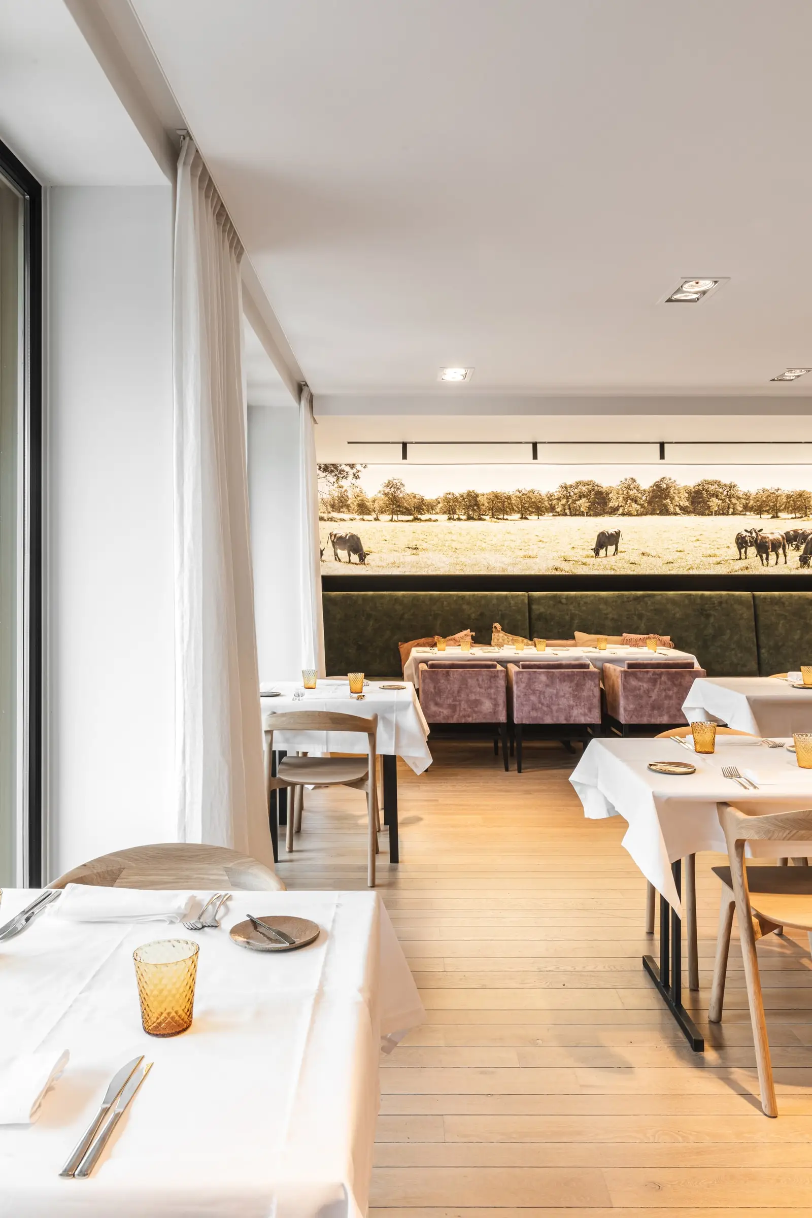 Eetzaal met witte gordijnen langs de ramen en gedekte tafels