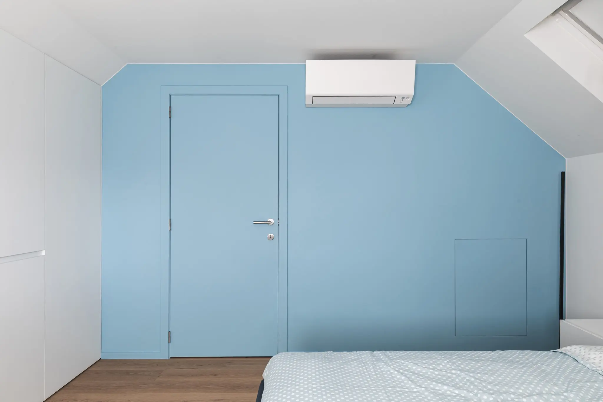 Slaapkamer met een lichtblauwe muur en een deur in dezelfde kleur, in een woning in Zulte
