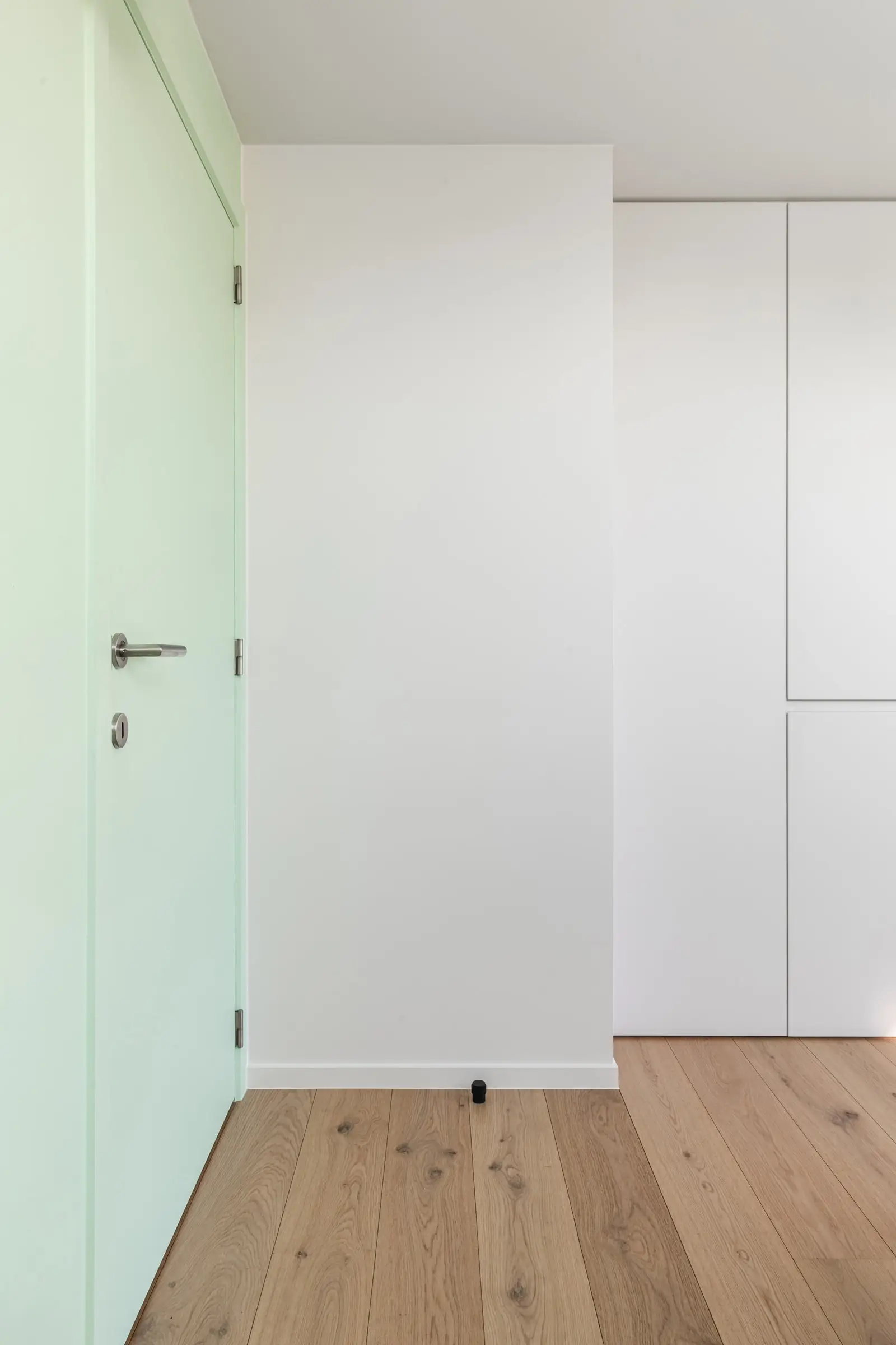 Mintgroene muur en witte kasten in een slaapkamer