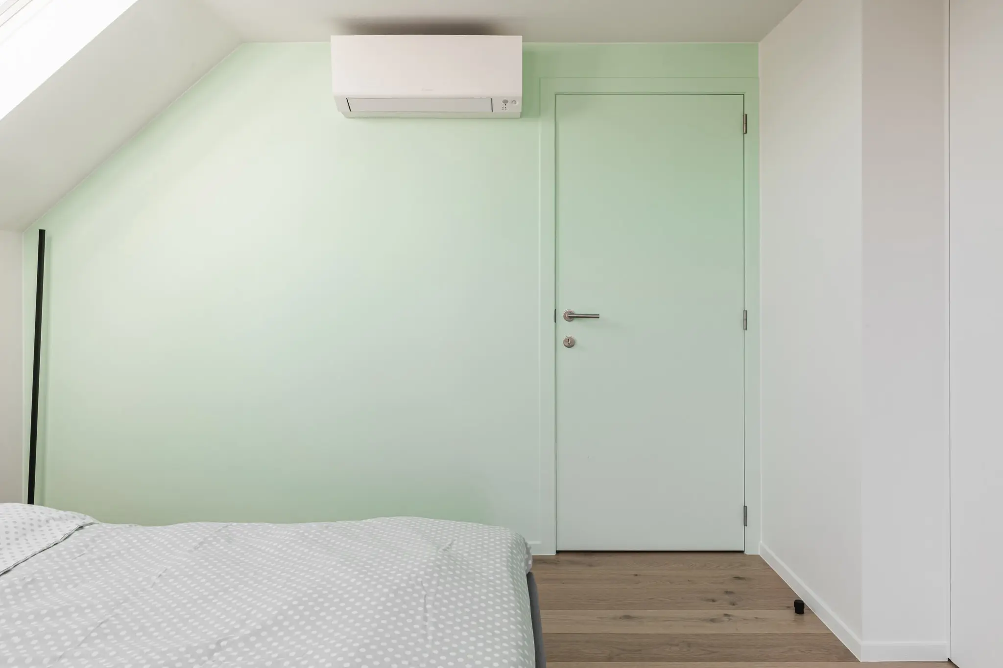 Slaapkamer onder het dak met een mintgroene muur, in een woning in Zulte