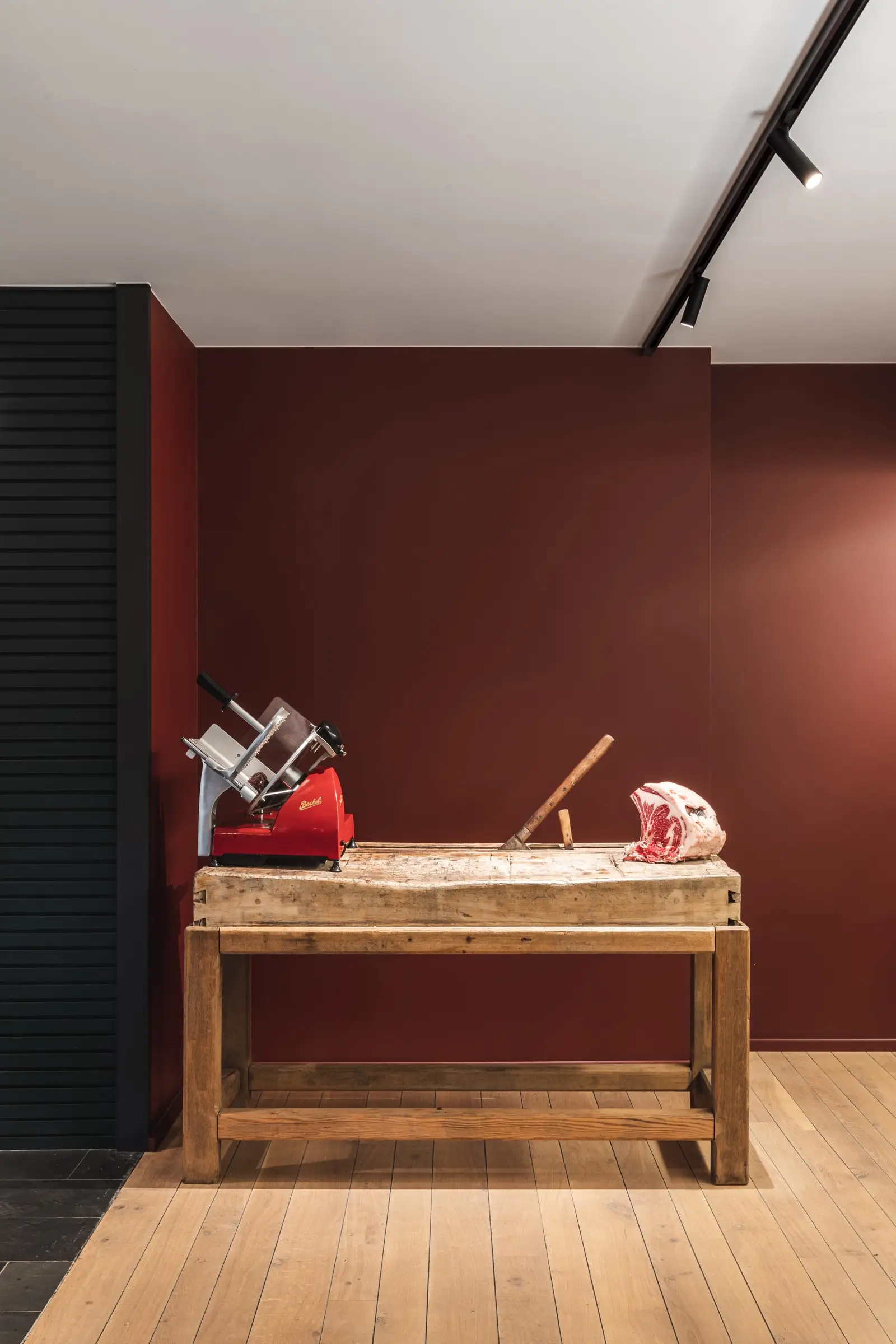 Houten slagerstafel met een snijmachine voor een diep rode muur