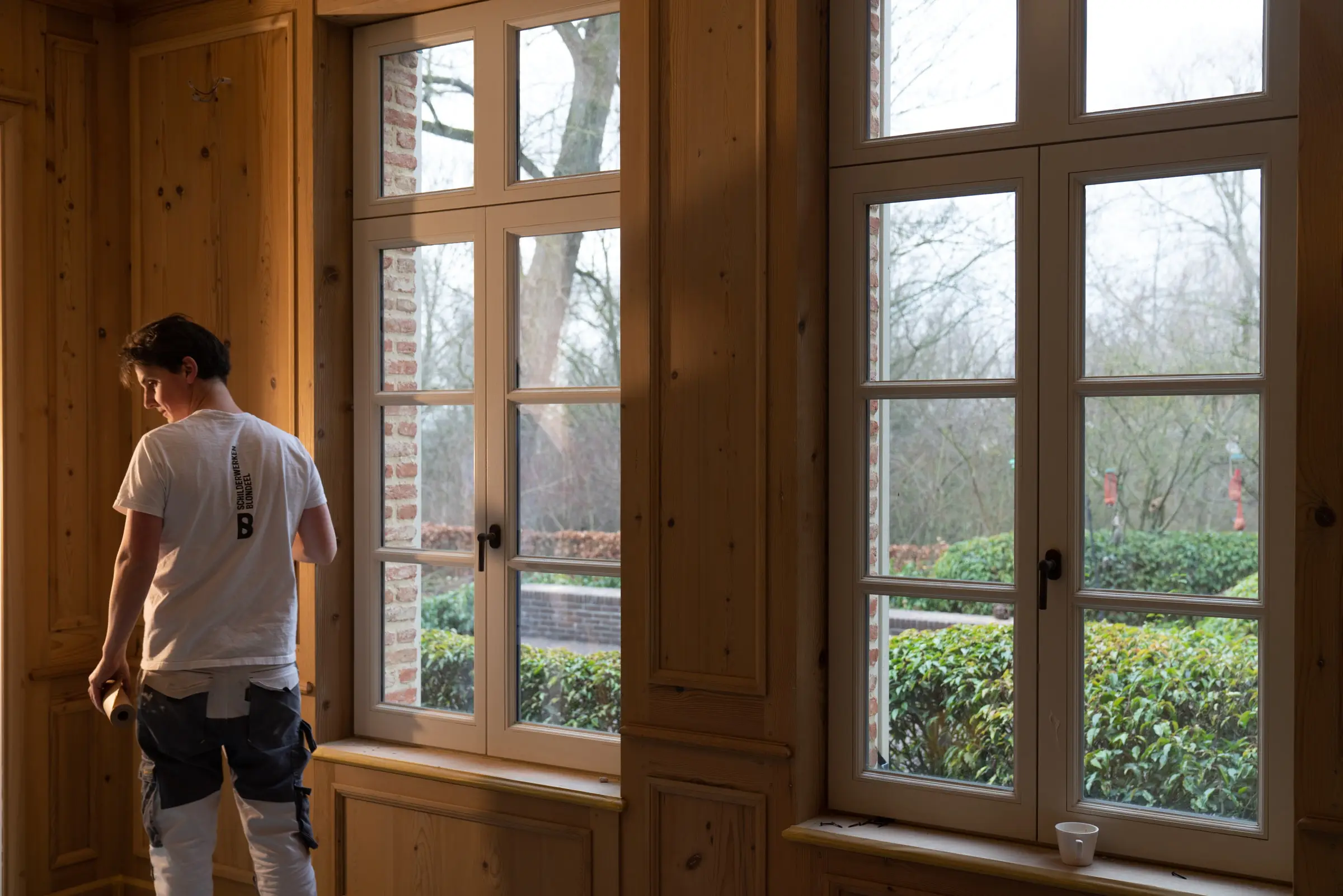 Timothy Blondeel aan het raam in een kamer met houten lambrisering
