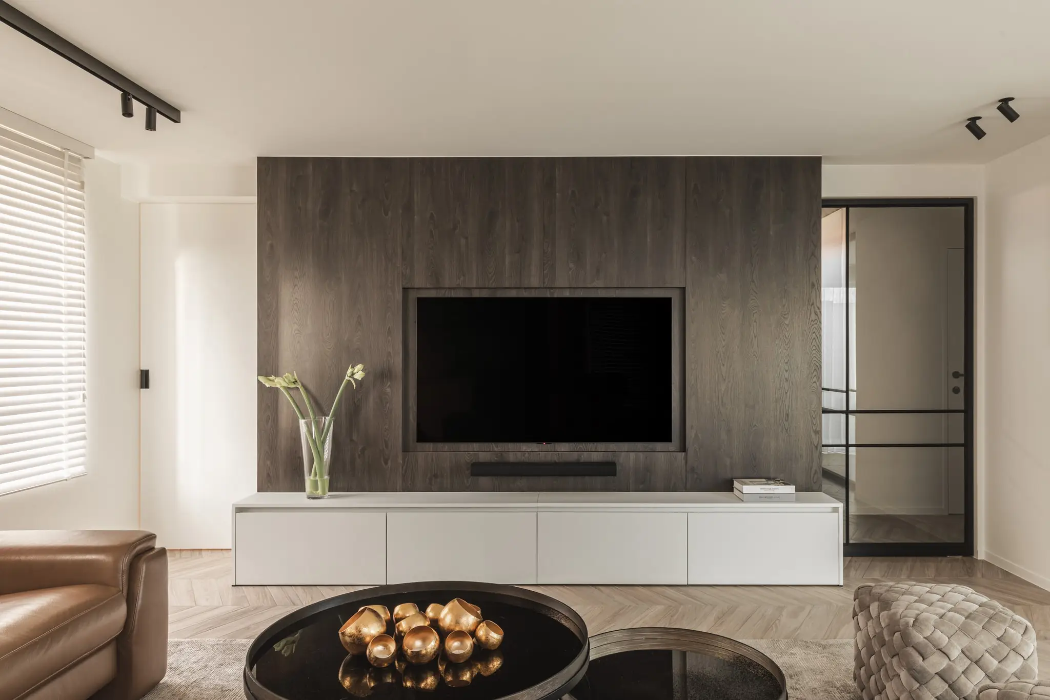 Leefruimte met een donkere houten tv-wand en witte muren