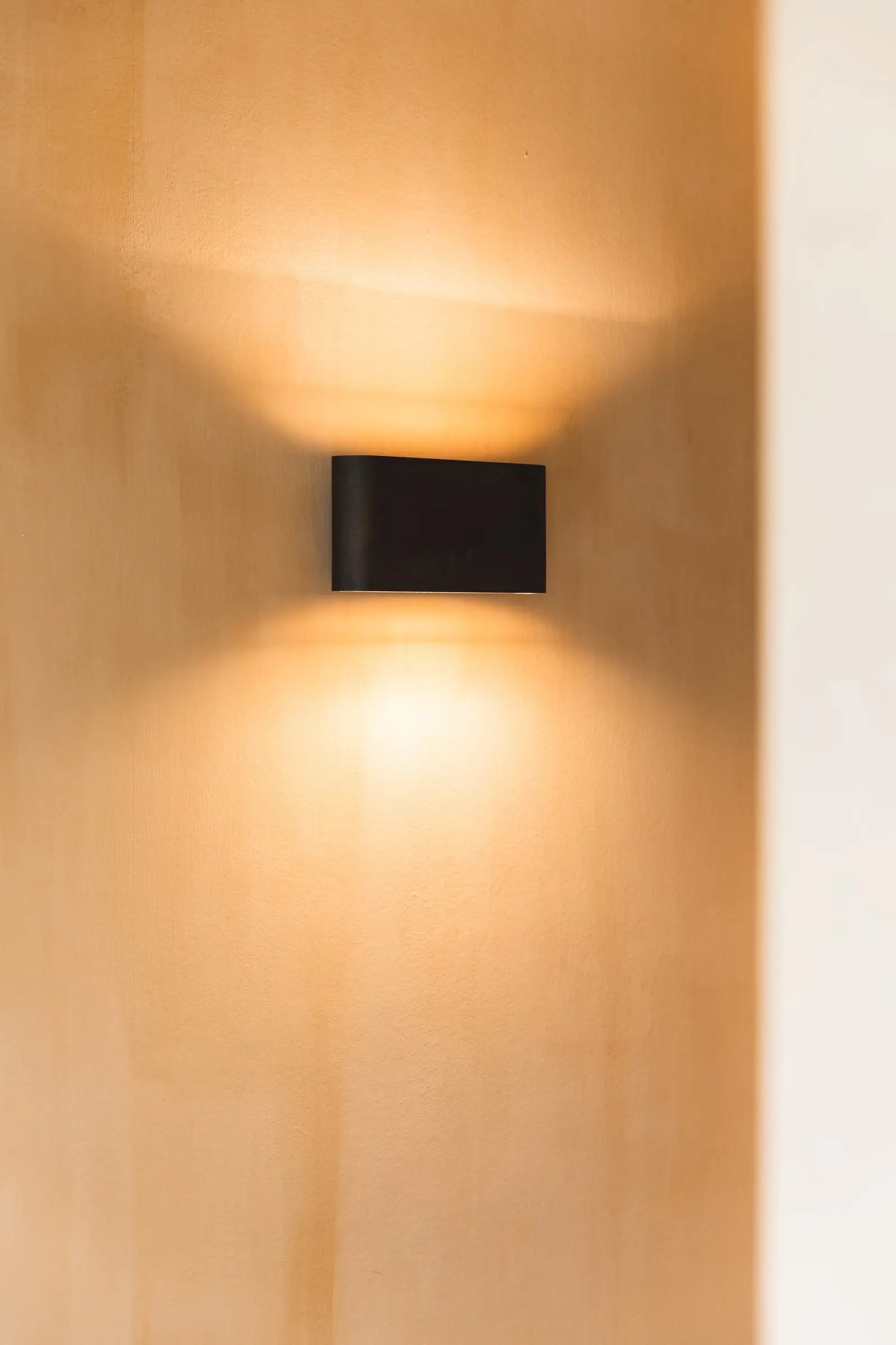 Zwarte wandlamp op een muur met een gevlekte okerafwerking